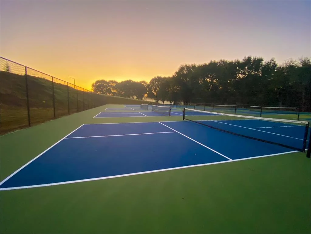 The Orchard tennis and pickleball courts at sunset, freshly surfaced with vibrant blue courts